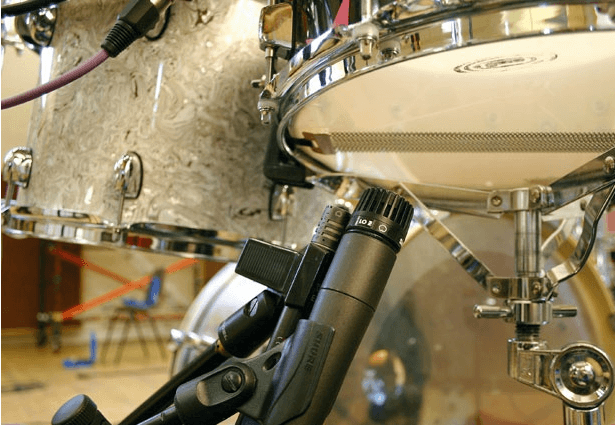 Micro sous la caisse claire pointé vers la peau de résonance — captation du timbre snare buzz